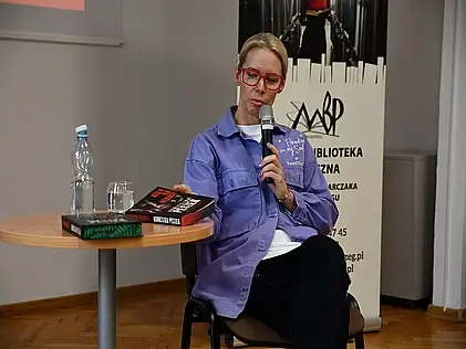 Spotkanie autorskie z Agnieszką Peszek. W ręku trzyma mikrofon i mówi do ludzi